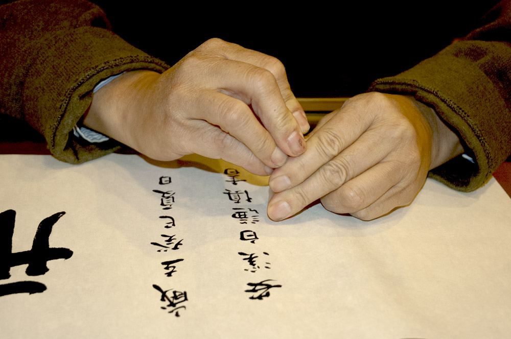 Qianshen Bai making impression using inked seal.