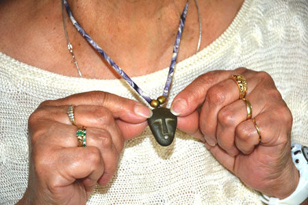 Patricia James-Perry holding a pendant necklace made by her son Jonathan James-Perry.