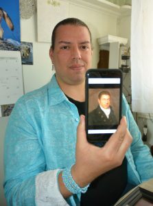Jonathan James-Perry holding up a portrait of his ancestor, whale man Henry Gray James.