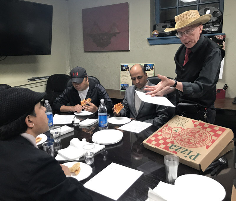 Group sitting around conference room table eating pizza. 