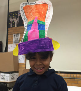 Smiling girl wearing a hat she made as part of a Creative Minds Out of School Time project.