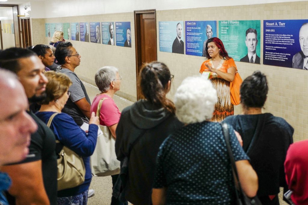 Michelle Guzman conducting tours of the hallway art guides a crowd through Mayors Row on the 3rd floor.