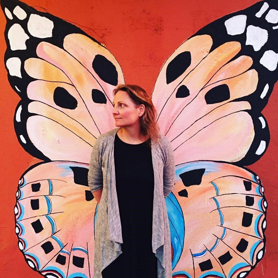 Sienna Wildfield in front of a butterfly mural.