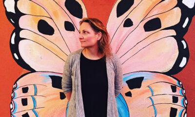 Sienna Wildfield in front of a Butterfly mural