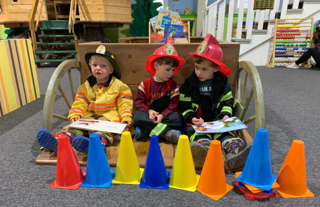 Three children dressed as firefighters play at Cape Cod Children's Museum.