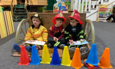 Three children dressed as firefighters play at Cape Cod Children's Museum.