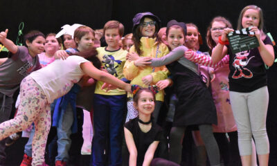 Children smiling on a stage with Enchanted Circle Theater