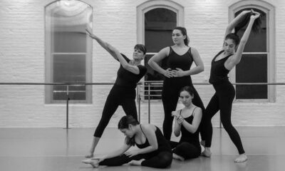 Five dancers in black leotards