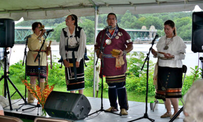 Four performers in native dress on a stage sing and play instruments