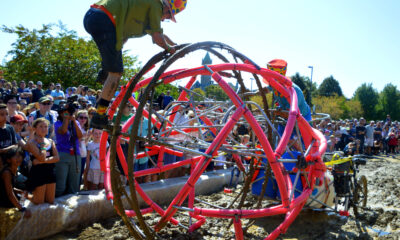 two people working to get their kinetic sculpture through a patch of mud while during the Lowell Kinetic Sculpture Race.