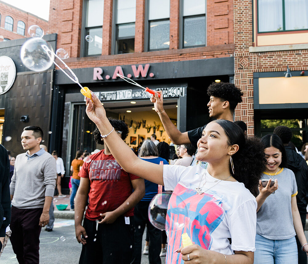 a group of young people blowing bubbles in front of Raw Art Works