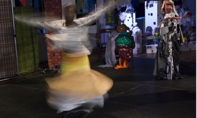 A woman is a blur twirling as part of a performance. Her arms extended over her head.