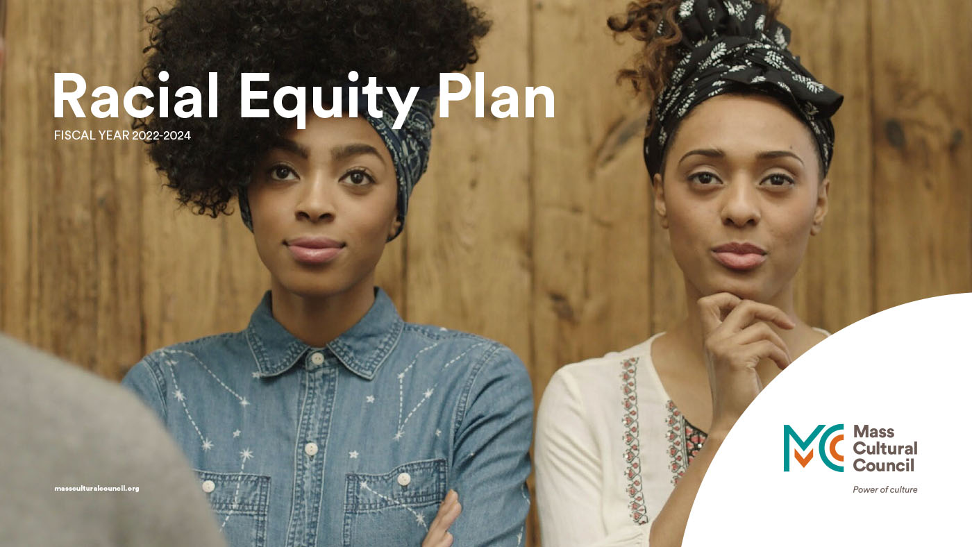 Two women of color standing side-by-side in front of wood paneling. They face forward. Each has what might be the verge of a smile on their faces.