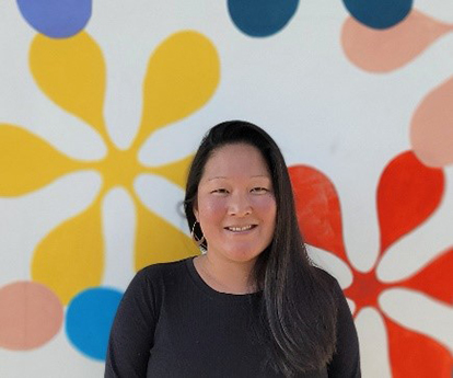 Catherine Cheng-Anderson stands in front of a wall covered in colorful amperstands and dots