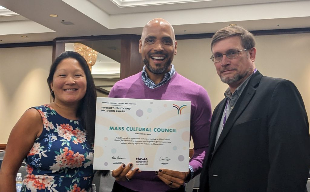 photo of 3 people standing with an award certificate