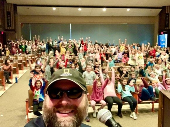 a photo of Dr. “The Machine” Jesse Green taking a selfie with a large crowd of excited students
