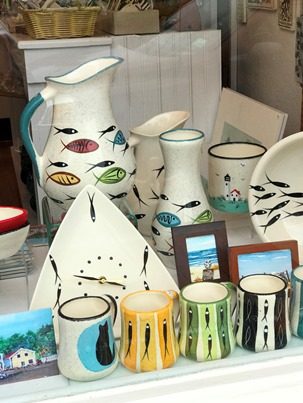 Pottery pieces with fish decorations in shop window.