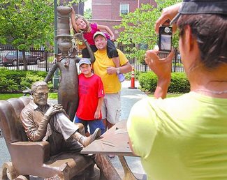 Family taking photos on a Dr. Suess sculpture in the quadrangle at the Springfield Museums