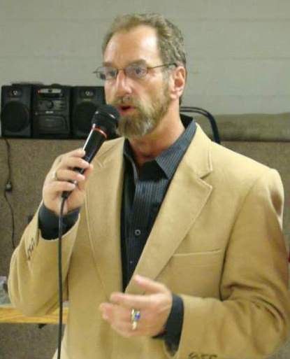 photo of Mark Snyder speaking into a handheld microphone