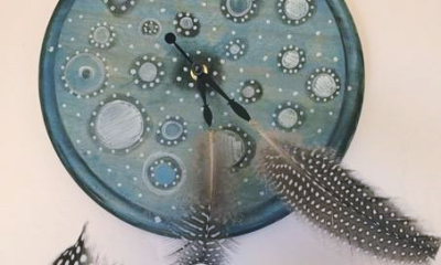 photo of an art piece where black and white polka dotted feathers are attached to the the hands of a clock