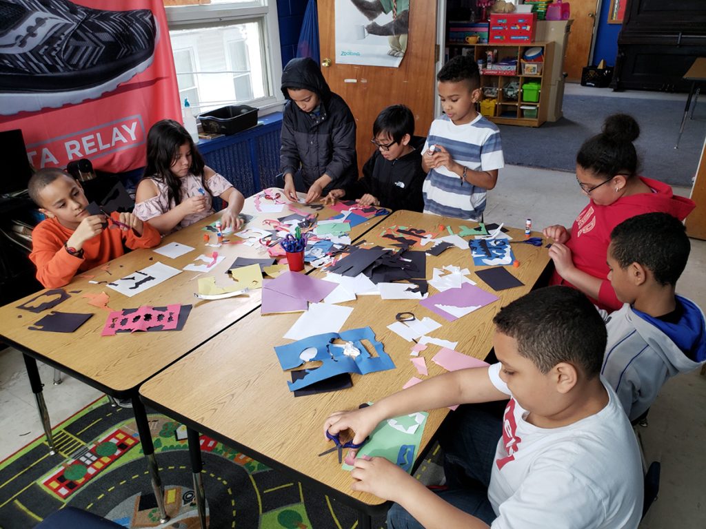 photo of kids cutting and assembling paper pieces around a large table