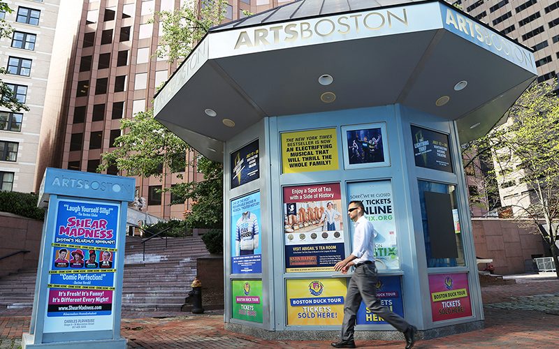 Person walking in front of Arts/Boston's ticket booth at Faneuil Hall