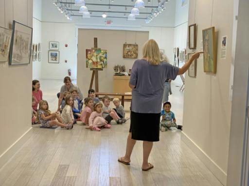 Pre-K children seated on the floor before a teacher in the Francine Kelly Gallery