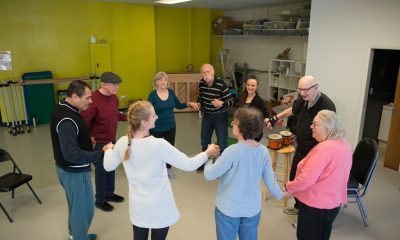 photo of elderly adults holding hands in a circle as part of a dance class
