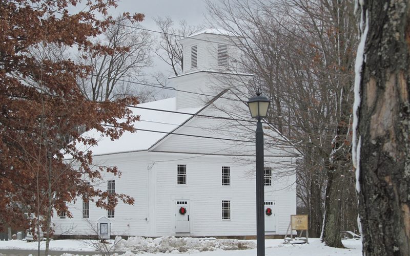 Snow carpeting the ground in front of the historic Wendell Meetinghouse