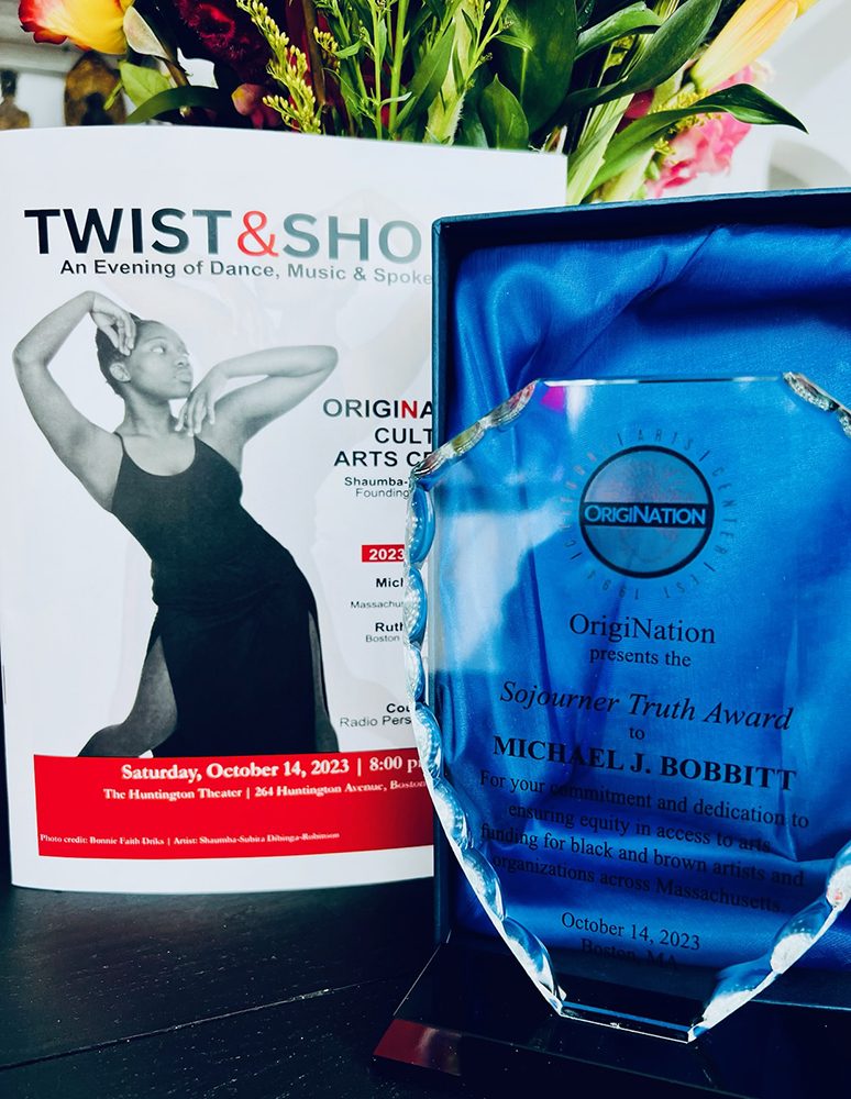 photo of a program cover for the Twist & Shout event and the award object for Michael J. Bobbitt's Sojourner Truth Award, a crystal plaque