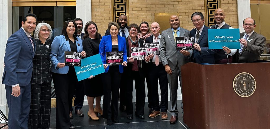 group photo of elected officials and arts leaders holding signs that read "What's your power of culture?" and "Celebrate Creativity"