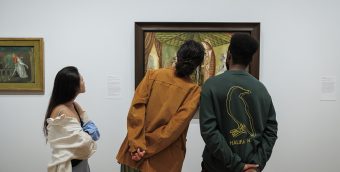 photo of the backs of 3 museum-goers heads, only sections of the painting they are looking are visible in the background
