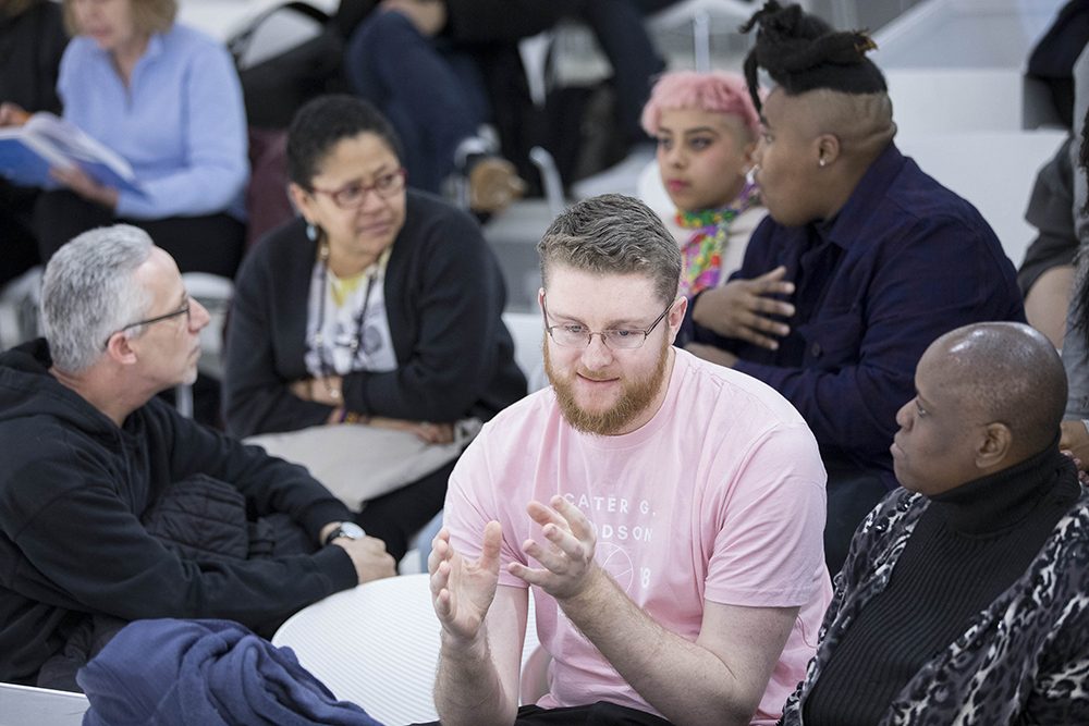 photo of a diverse range of people sitting in different small groups talking to one another