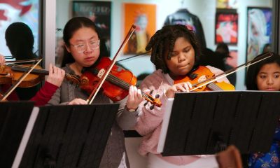 photo of half a dozen youth musicians playing string instruments tucked under their chins.