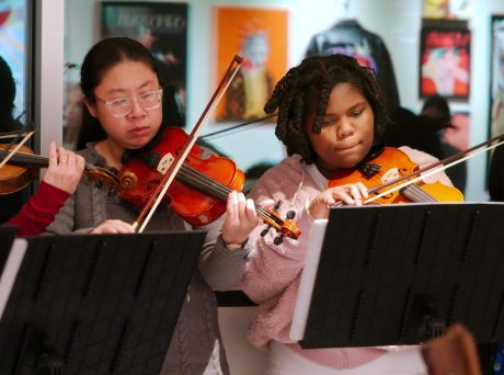 photo of half a dozen youth musicians playing string instruments tucked under their chins.