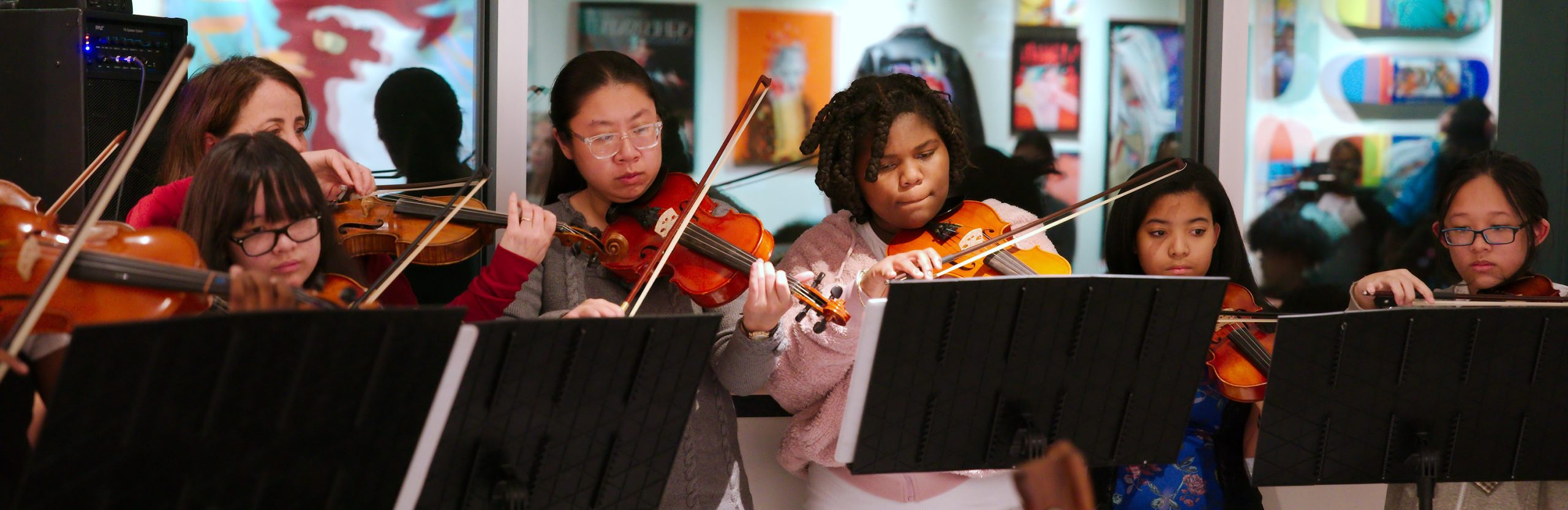 photo of half a dozen youth musicians playing string instruments tucked under their chins.