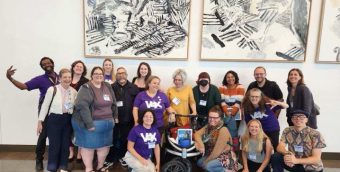 group photo of 18 people smiling in an art gallery