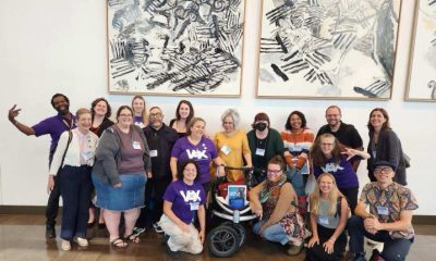 group photo of 18 people smiling in an art gallery