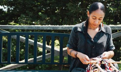 photo of a woman seated outside weaving.