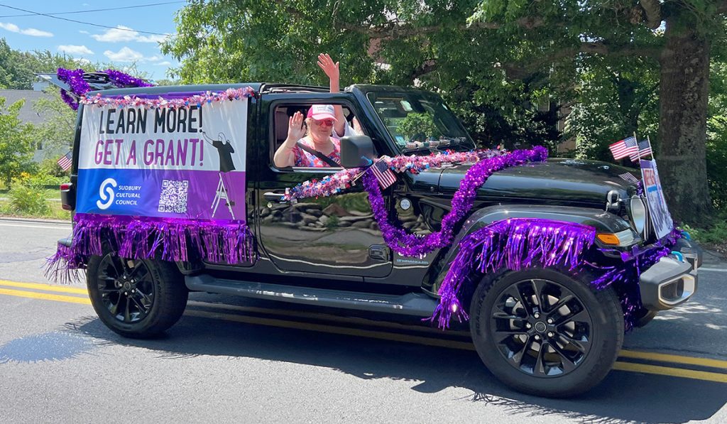 photo of a black Jeep covered in purple shimmery garland and a large banner that reads Learn More, Get a Grant.