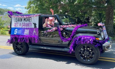 photo of a black Jeep covered in purple shimmery garland and a large banner that reads Learn More, Get a Grant.