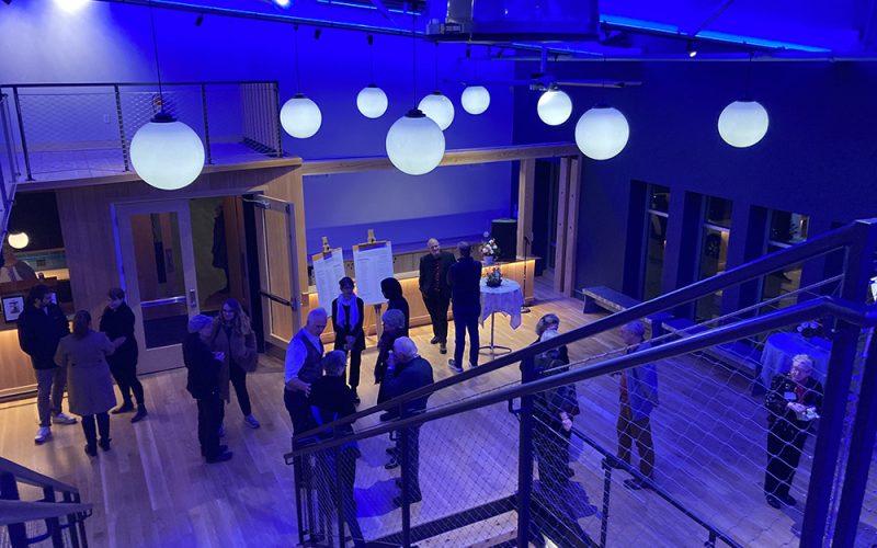 People gathered in the lobby under blue lighting at the Northampton Community Arts Trust