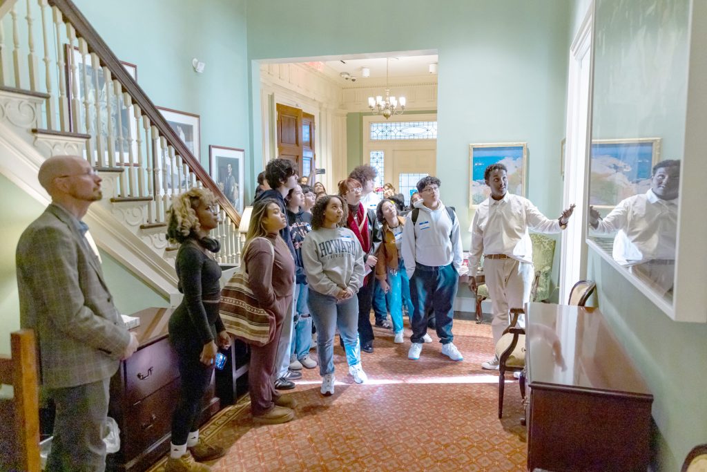 photo of young people looking at art hanging in the Executive Suite of the State House.
