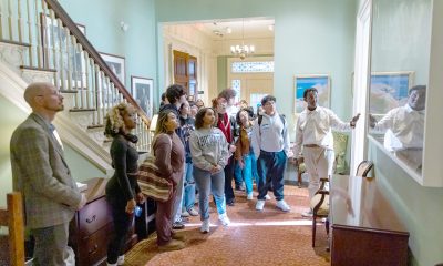 photo of young people looking at art hanging in the Executive Suite of the State House