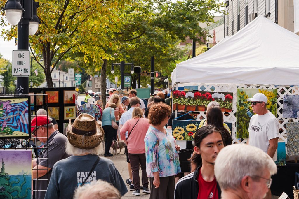 photo of a busy street fair with artists selling their paintings and people milling around.