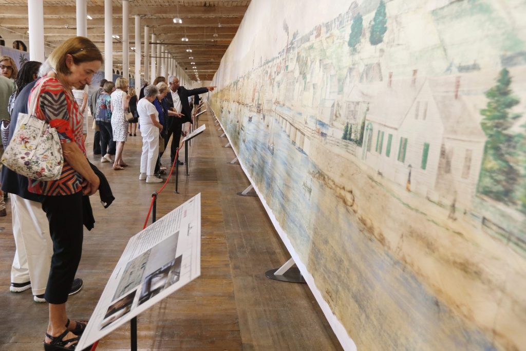 photo of people standing along a wall of a gallery looking at a panoramic painting at tall as the room and longer than the Empire State Building.