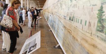 photo of people standing along a wall of a gallery looking at a panoramic painting at tall as the room and longer than the Empire State Building.