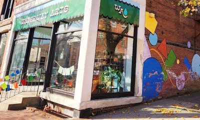 photo of a colorful storefront on the corner of a town's main street. Along the side of the building is a mural of large, brightly colored geometric shapes.