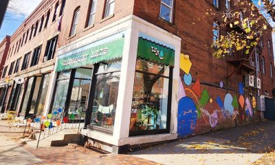 photo of a colorful storefront on the corner of a town's main street. Along the side of the building is a mural of large, brightly colored geometric shapes.