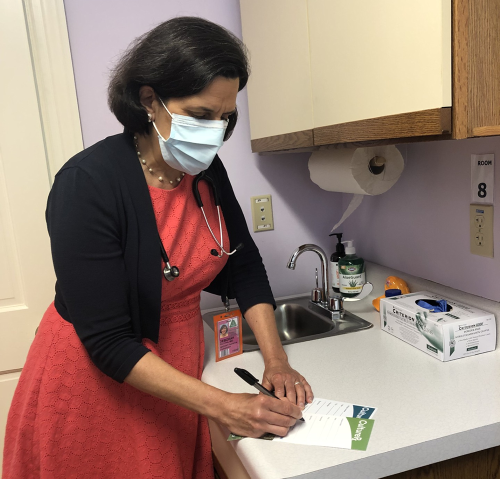 photo of a doctor in an examination room writing an arts prescription